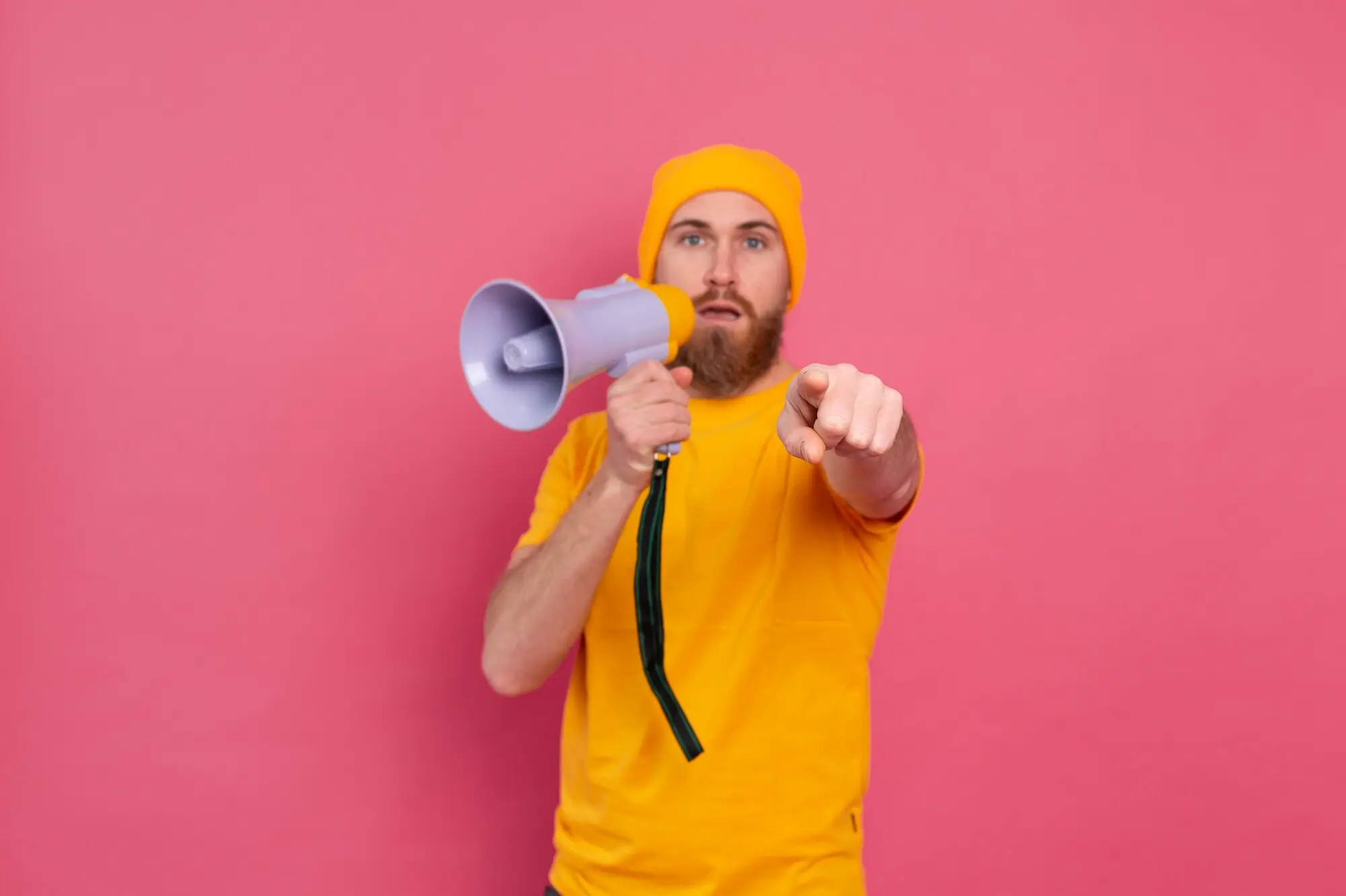 Achtung! Ein europäischer Mann mit Megafon zeigt mit dem Finger auf die Kamera, vor pinkem Hintergrund, praxisnah und nachvollziehbar.
